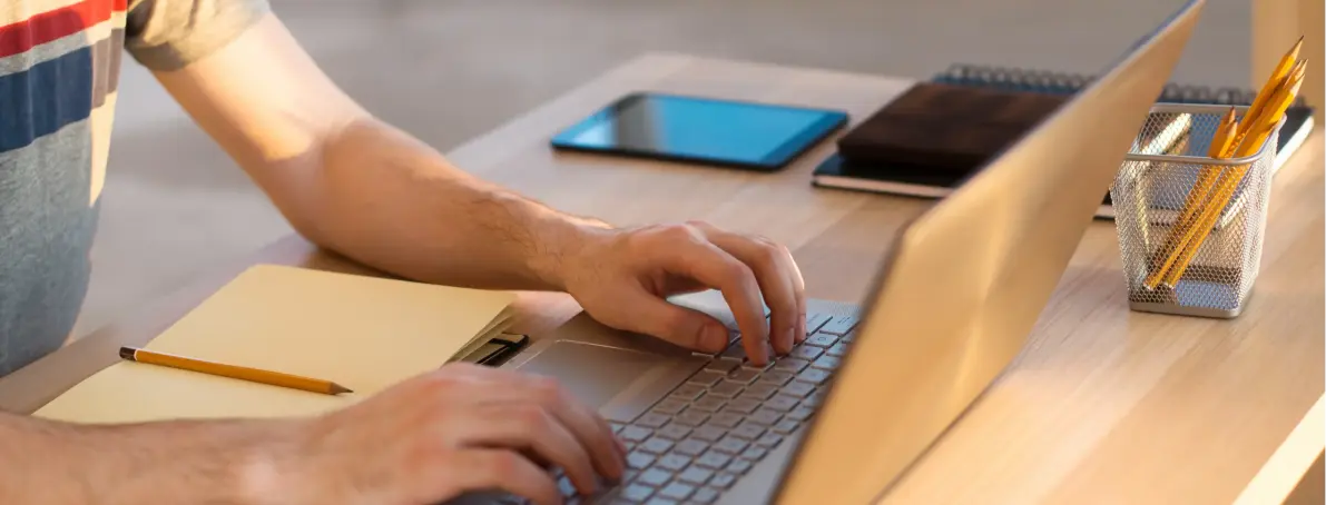 Person learning web scraping basics on laptop at organized workspace with notebooks and supplies